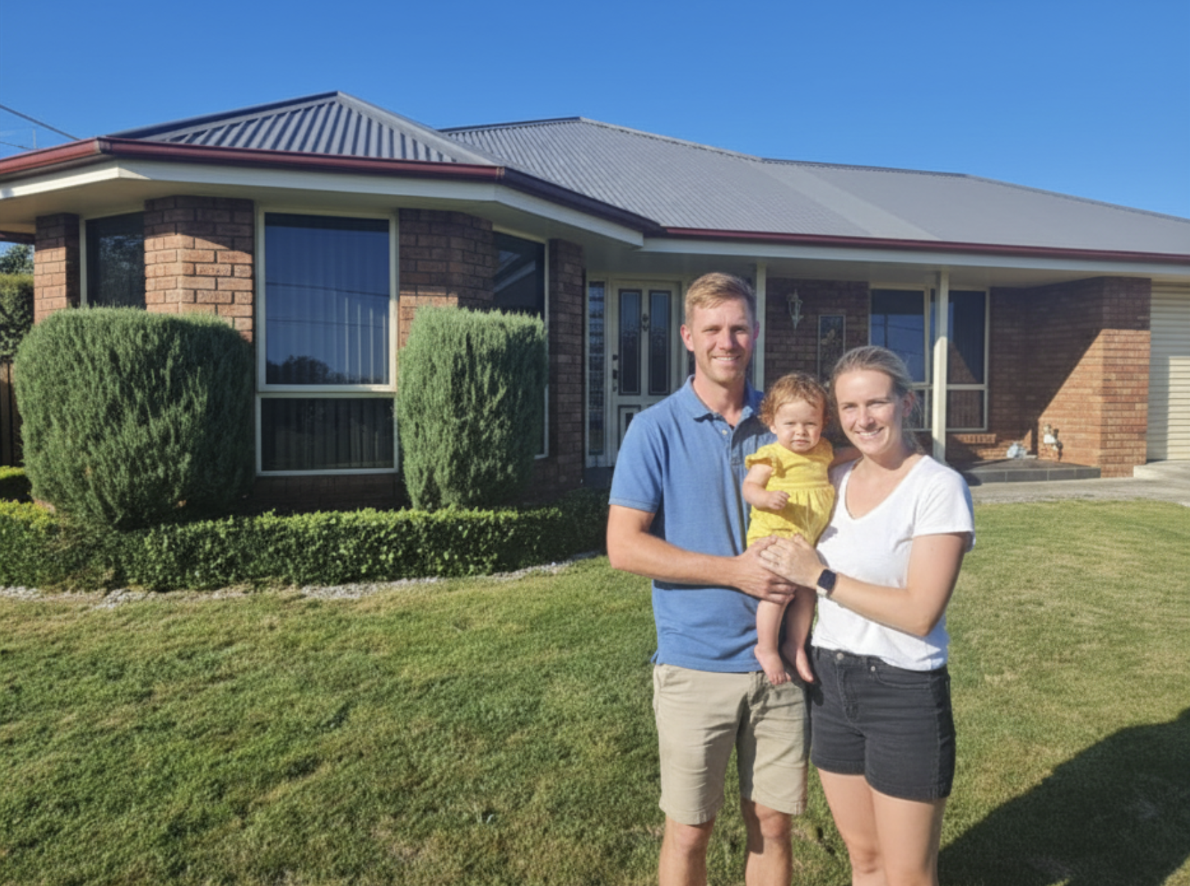 Happy family standing in front of their new home